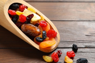 Photo of Scoop with different dried fruits on wooden background, space for text. Healthy lifestyle