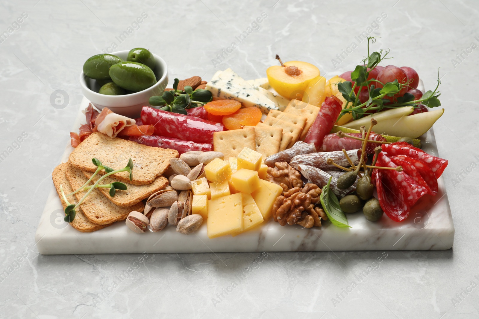 Photo of Board with different tasty appetizers on light marble table