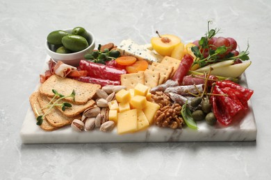 Board with different tasty appetizers on light marble table