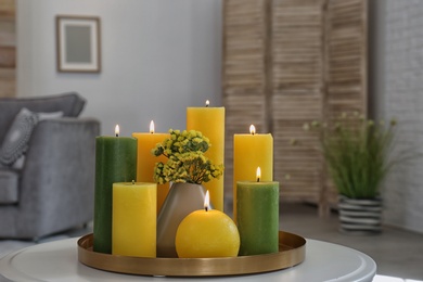 Photo of Tray with burning candles on table in living room