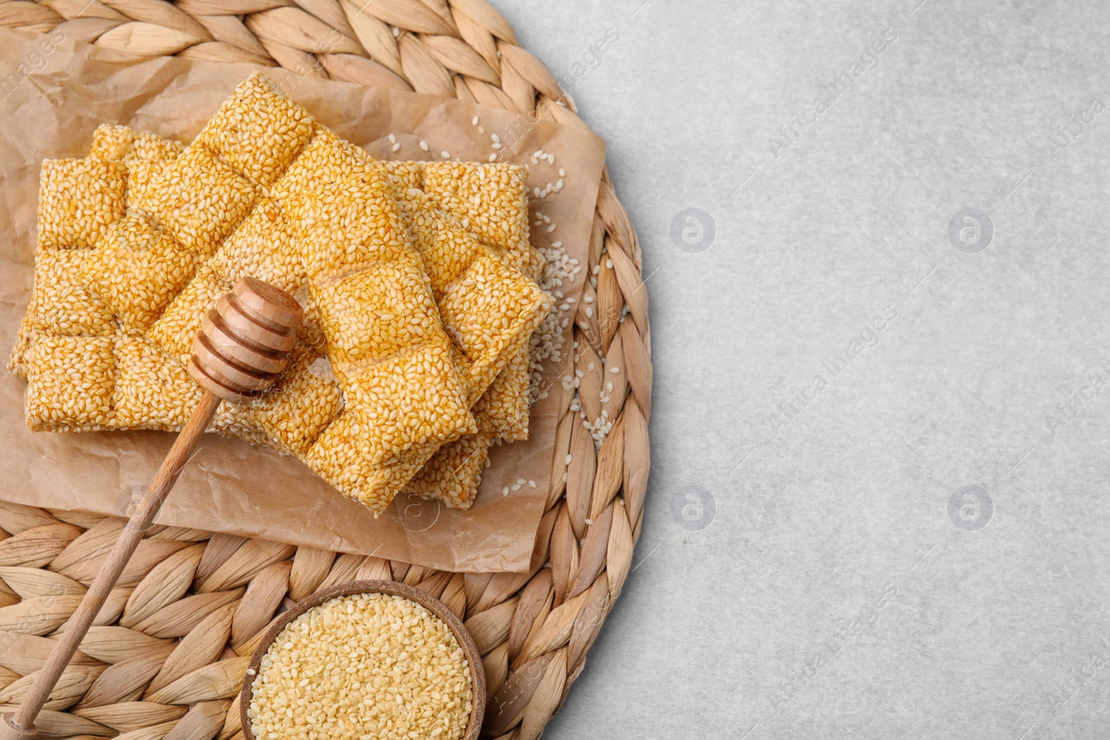 Photo of Delicious sweet kozinaki bars, sesame seeds and wooden dipper on light grey table, flat lay. Space for text