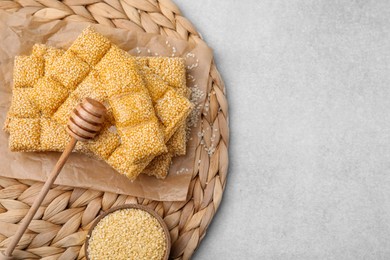 Photo of Delicious sweet kozinaki bars, sesame seeds and wooden dipper on light grey table, flat lay. Space for text