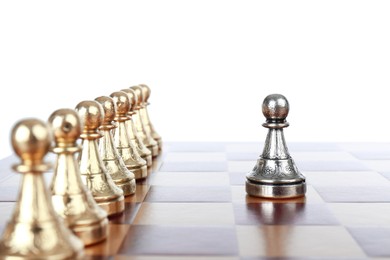 Photo of Silver pawn in front of golden ones on wooden chess board against white background