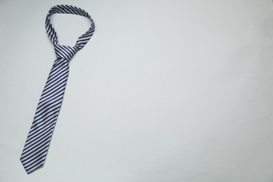 Photo of Striped necktie on light background, top view. Space for text