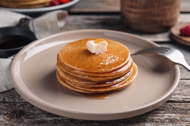 Tasty pancakes with butter and honey on wooden table, closeup