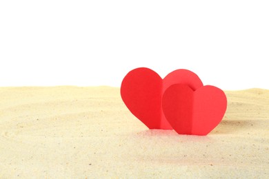 Photo of Honeymoon concept. Two red paper hearts and sand isolated on white