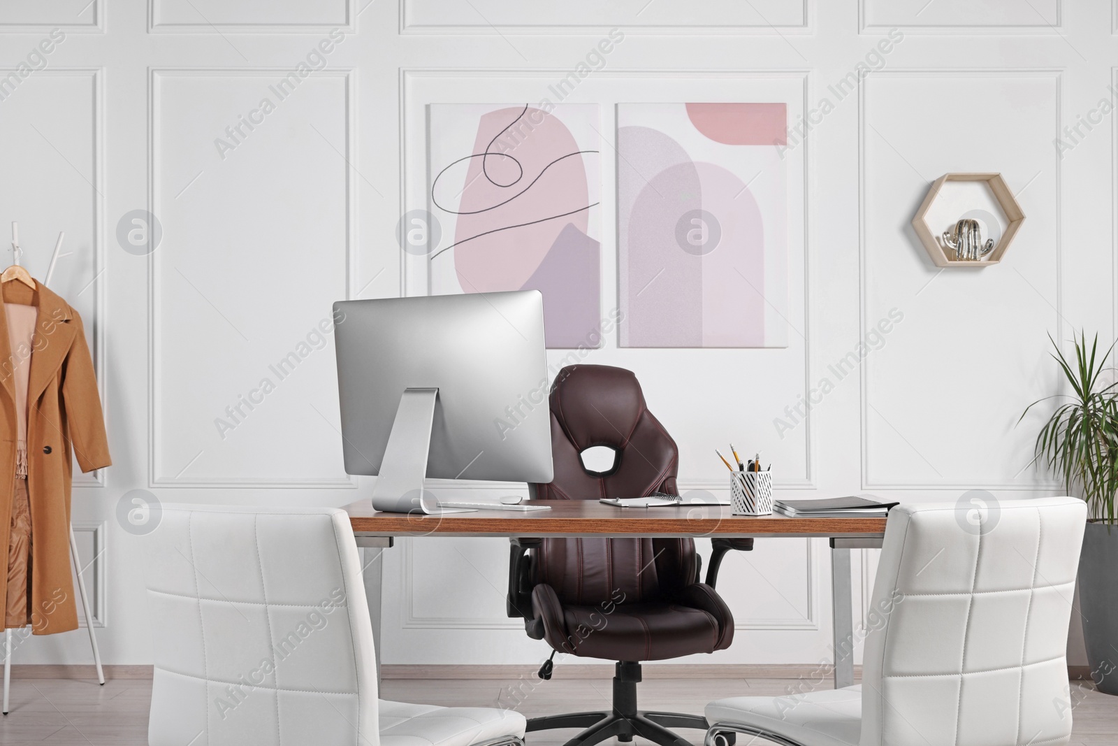 Photo of Director's workplace with wooden table, computer and comfortable armchairs. Interior design