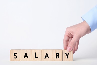 Image of Woman making word Salary with wooden cubes on white background, closeup
