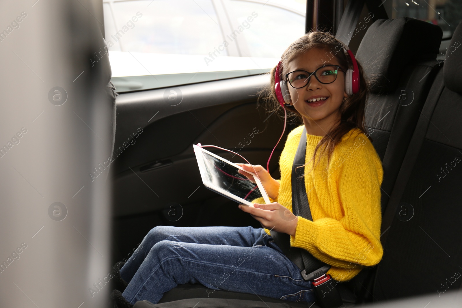 Photo of Cute little girl listening to audiobook in car