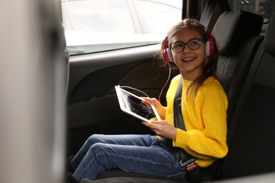 Cute little girl listening to audiobook in car
