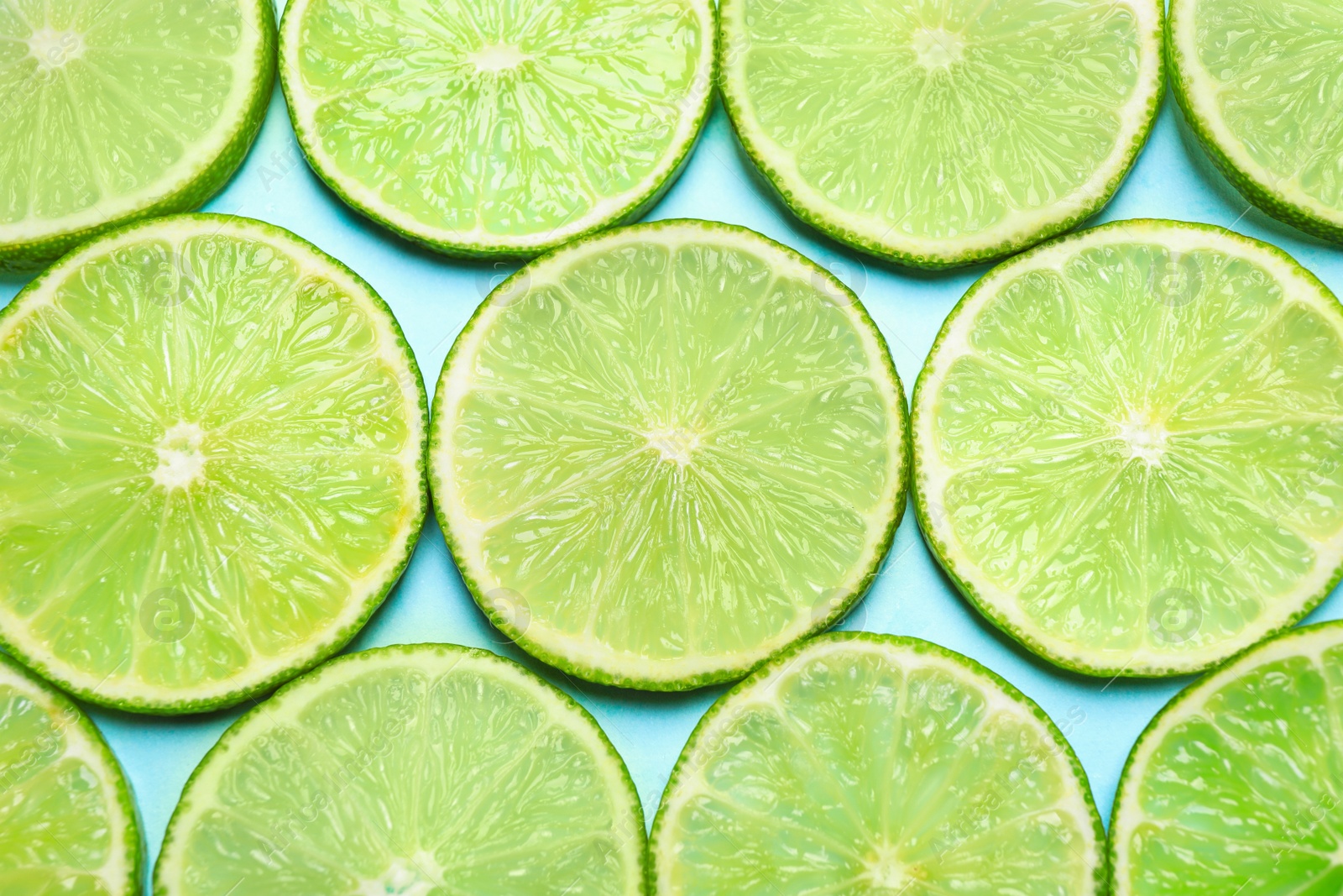 Photo of Juicy fresh lime slices on light blue background, flat lay