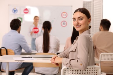 Photo of Happy woman at desk in class during lesson in driving school