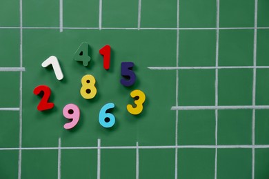 Photo of Many colorful numbers on green chalkboard, flat lay