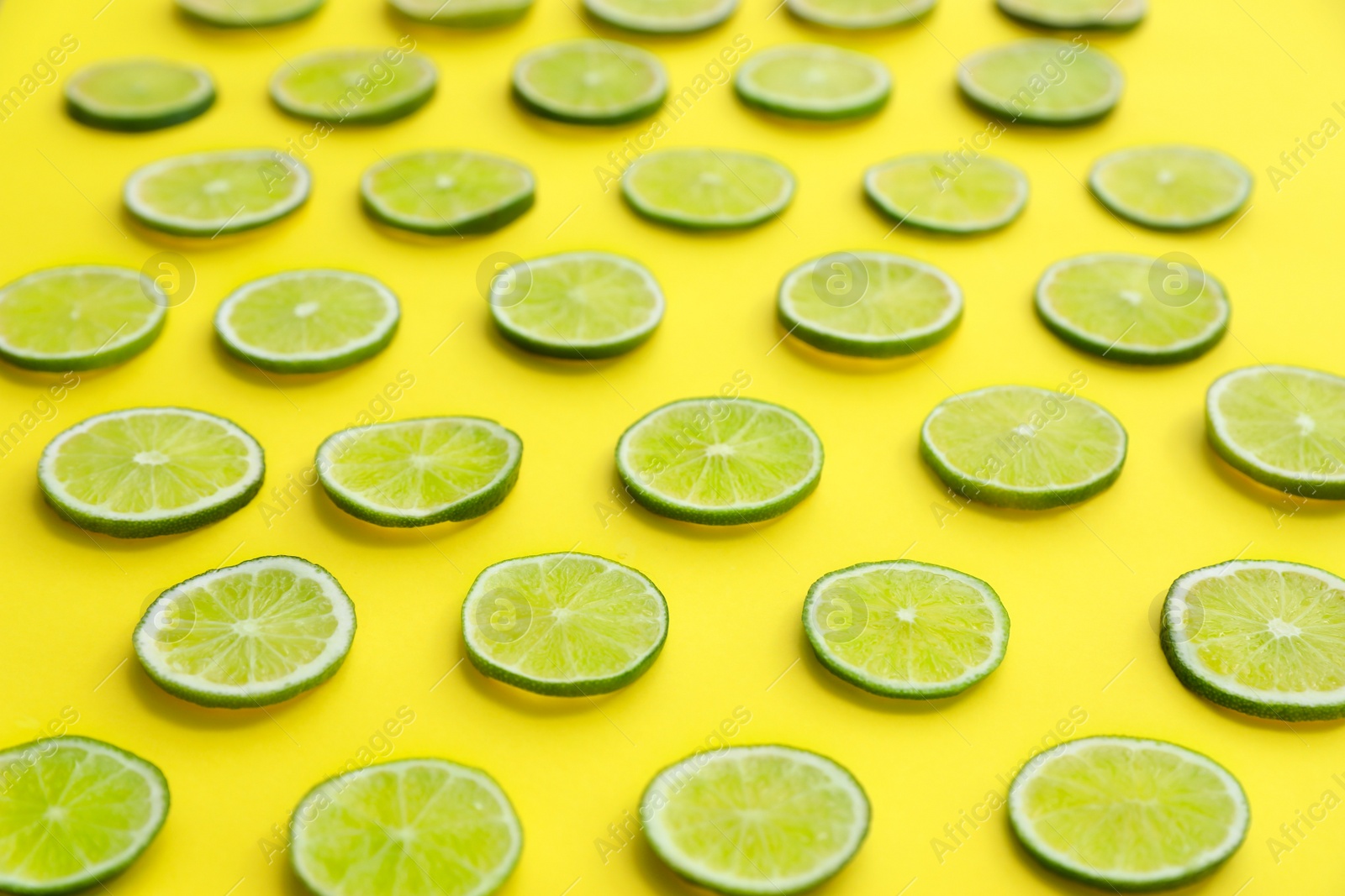 Photo of Slices of fresh juicy limes on yellow background