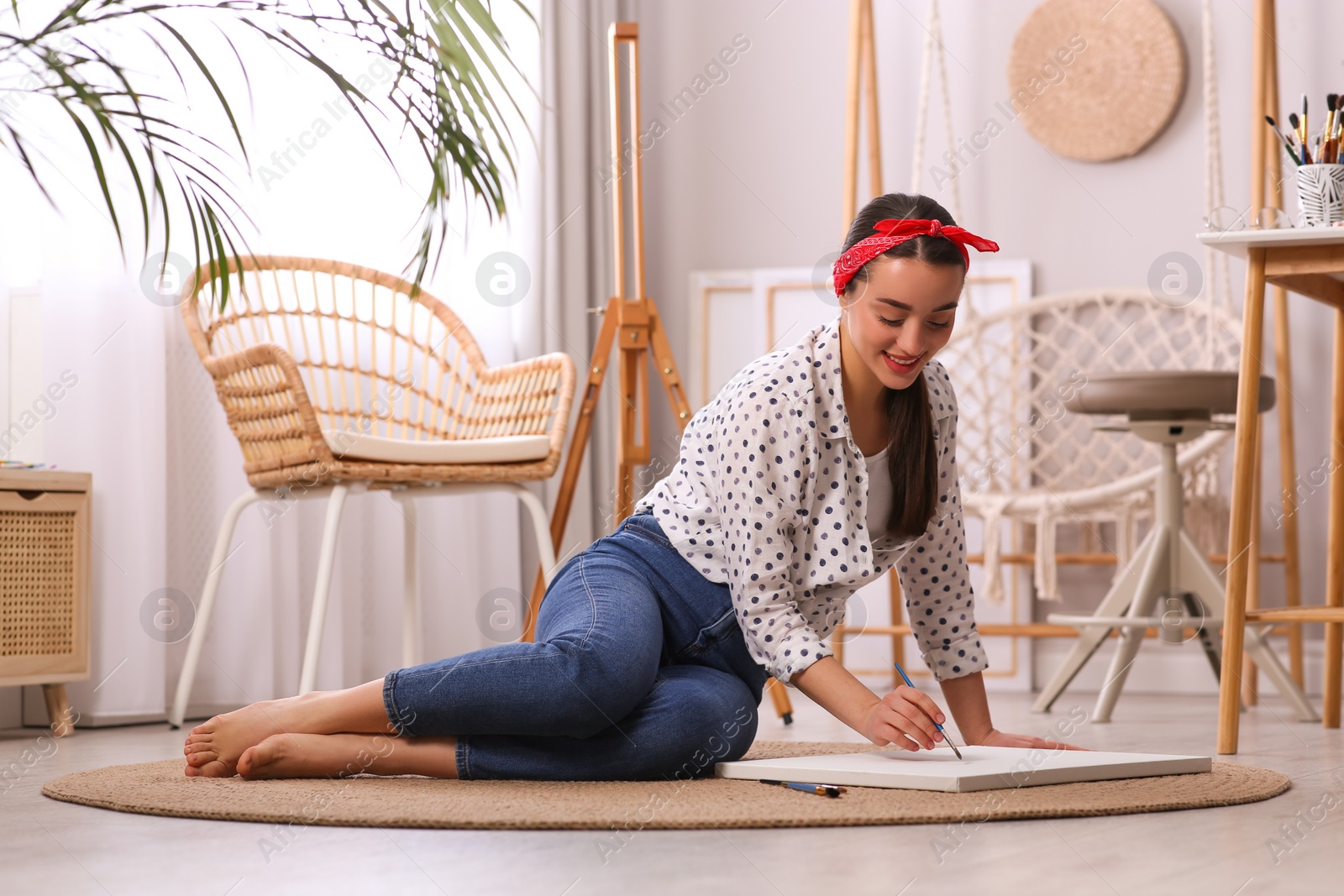 Photo of Happy woman artist drawing picture on canvas in studio