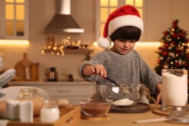 Photo of Cute little boy making Christmas cookies in kitchen