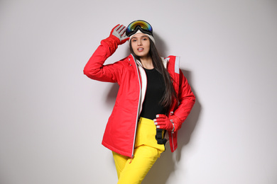 Woman wearing stylish winter sport clothes on light grey background