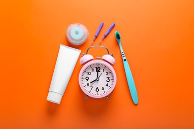 Photo of Flat lay composition with dental floss, alarm clock and different teeth care products on orange background