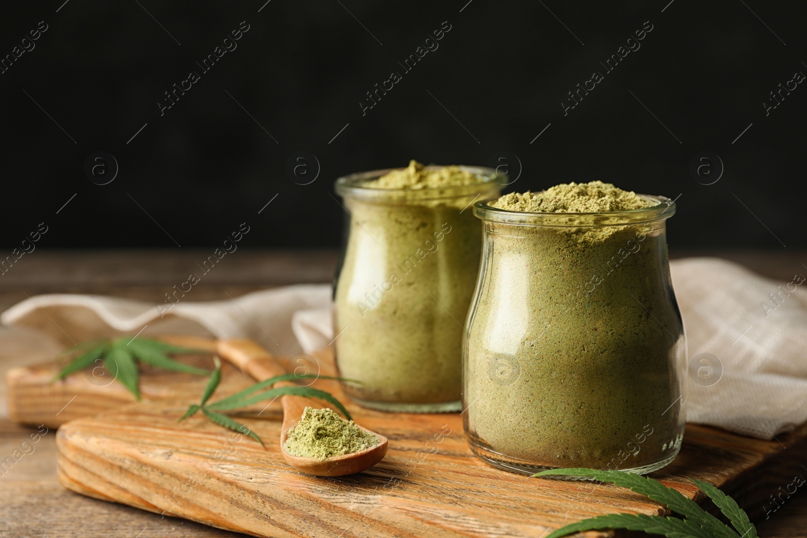 Photo of Jars of hemp protein powder on wooden table against black background. Space for text