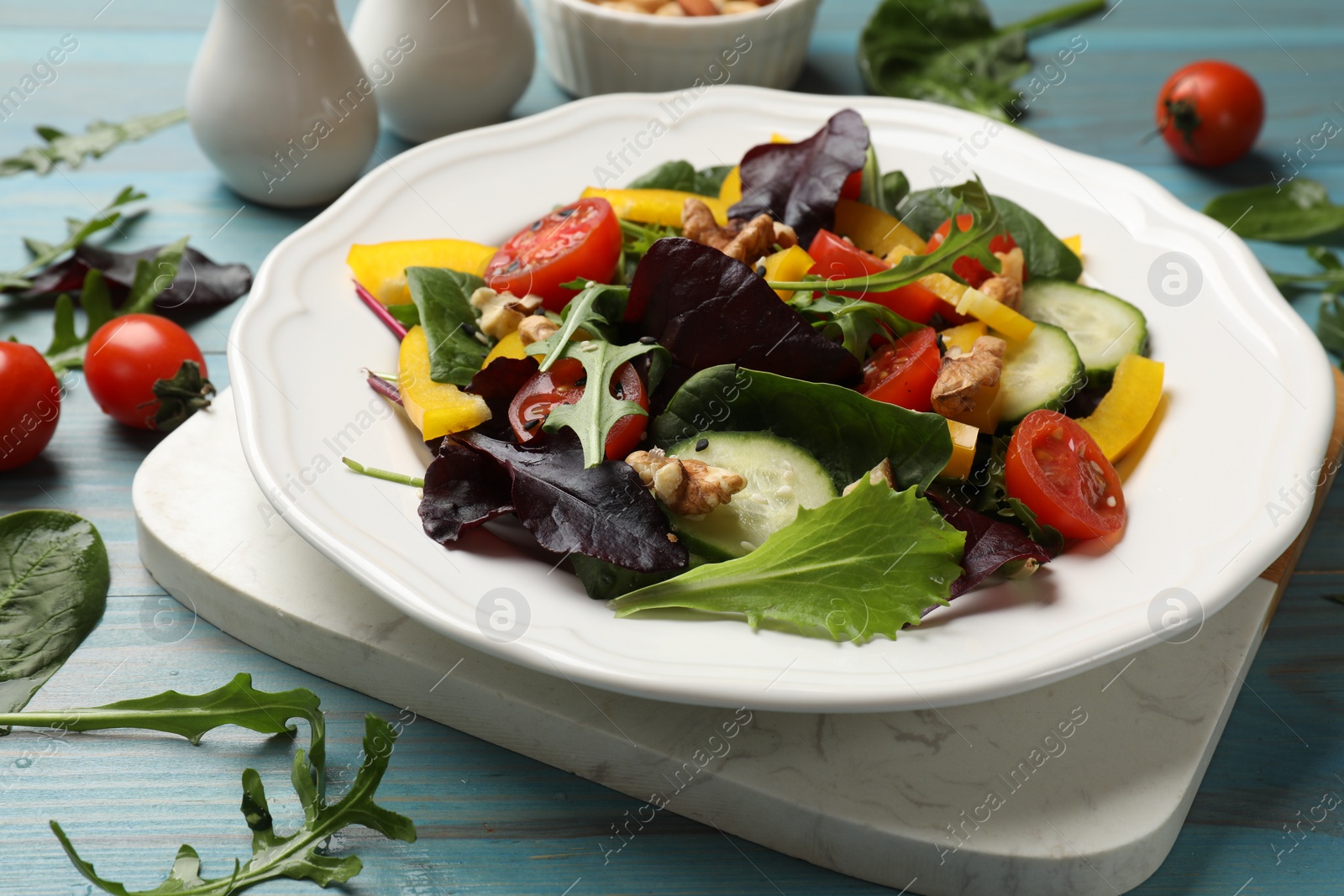 Photo of Tasty fresh vegetarian salad on light blue wooden table, closeup