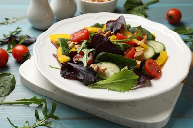 Tasty fresh vegetarian salad on light blue wooden table, closeup