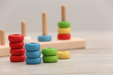 Photo of Motor skills development. Stacking and counting game pieces on light wooden table, space for text
