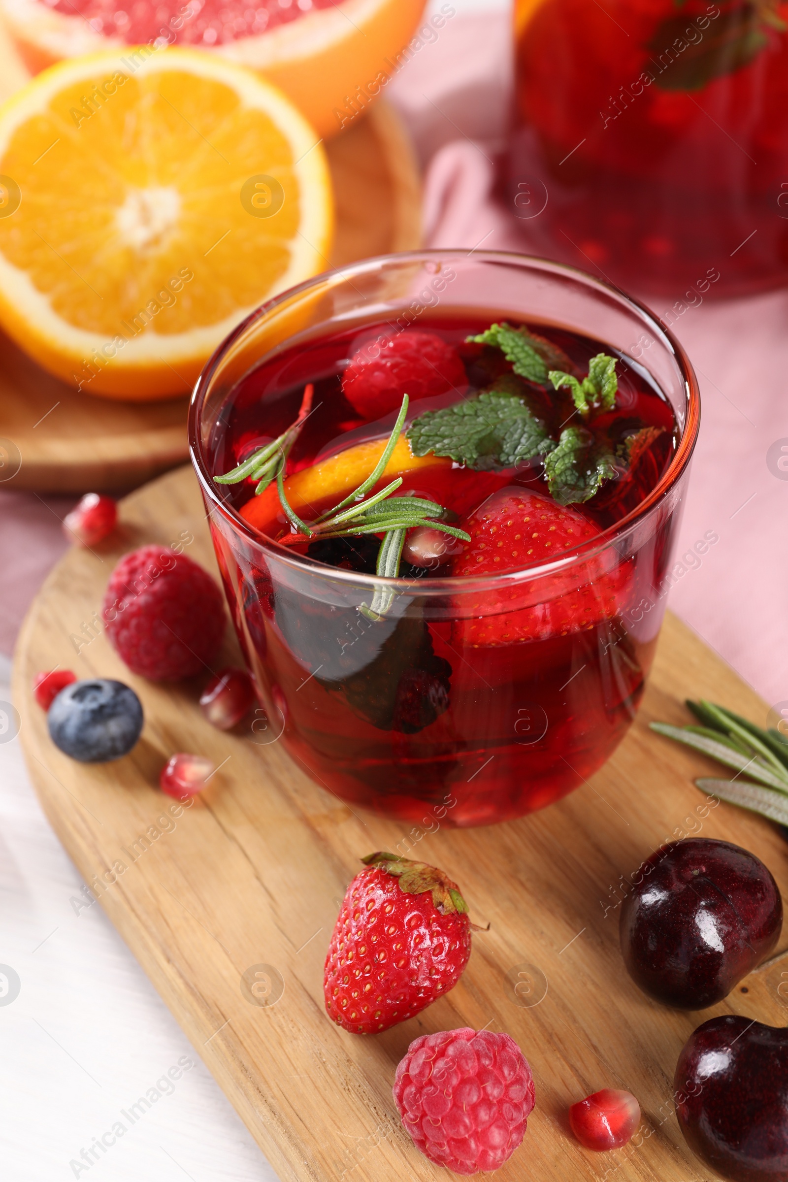 Photo of Glass of delicious sangria, fruits and berries on table