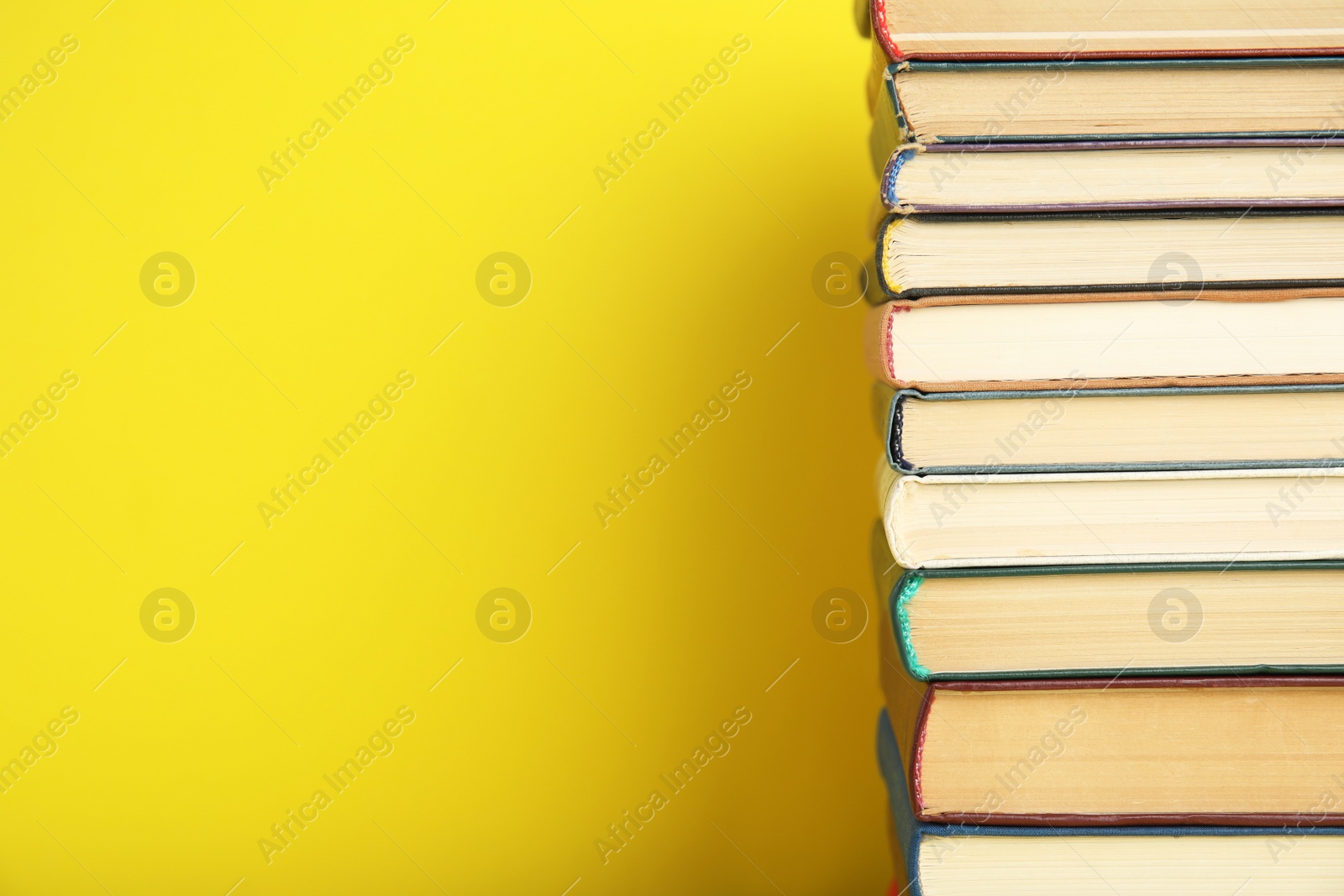 Photo of Stack of hardcover books on yellow background. Space for text