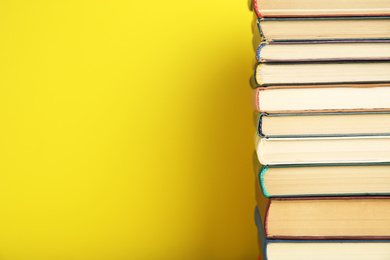 Photo of Stack of hardcover books on yellow background. Space for text