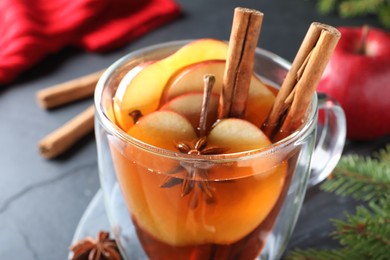 Photo of Aromatic hot mulled cider on black table, closeup