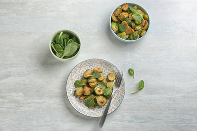 Photo of Delicious roasted brussels sprouts with basil served on white wooden table, flat lay
