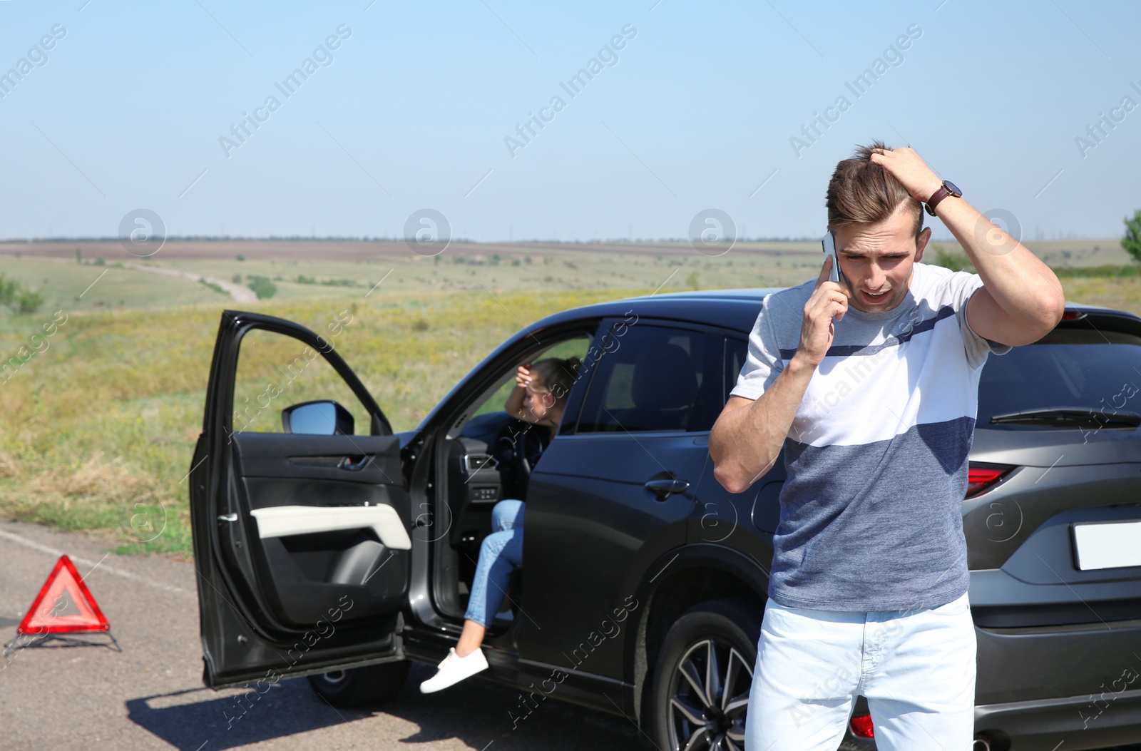 Photo of Man talking on phone near broken car outdoors