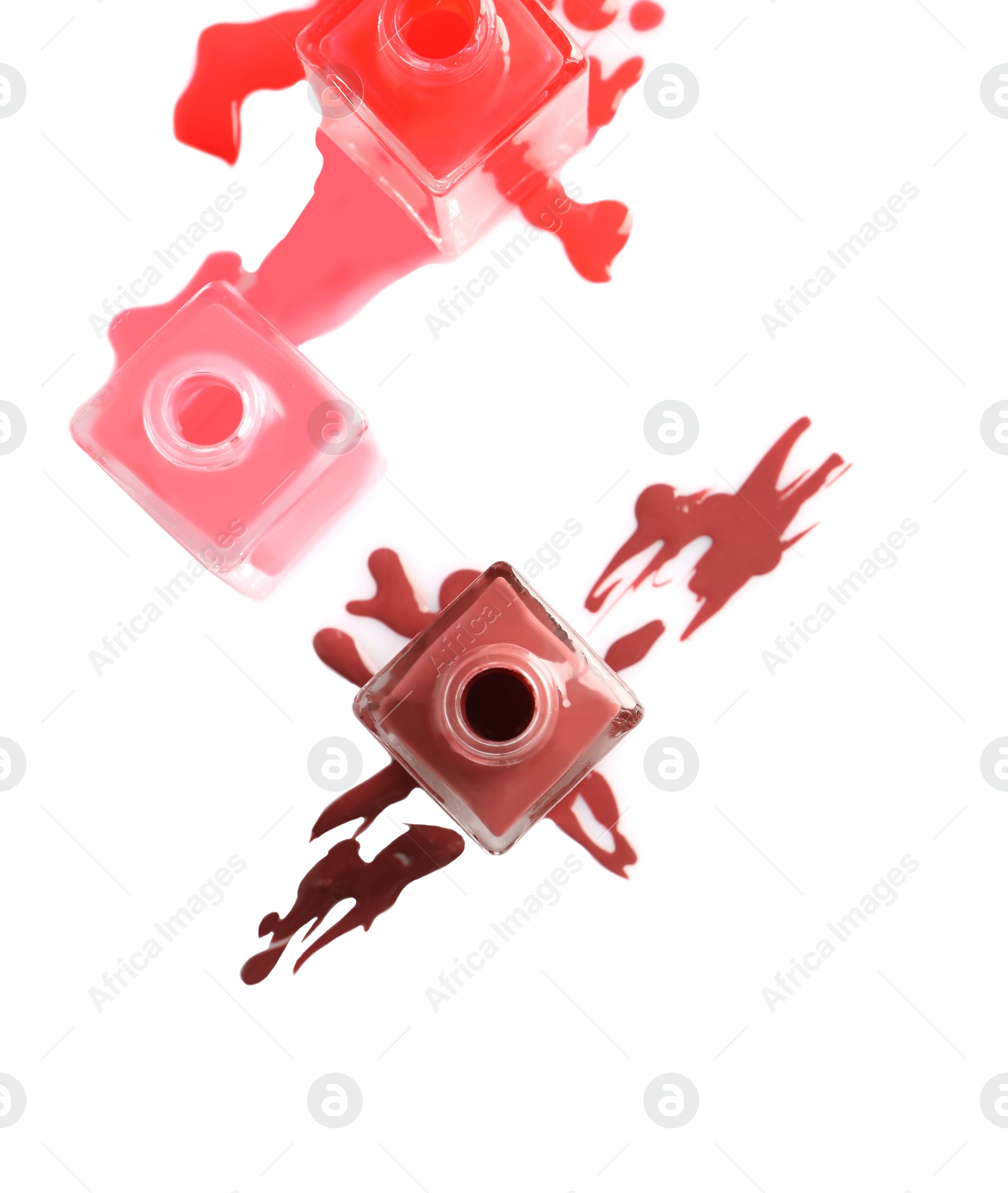 Photo of Spilled different nail polishes with bottles on white background, top view