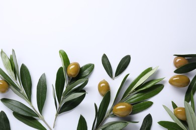 Fresh green olives and leaves on white background, flat lay. Space for text