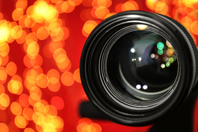 Photo of Modern video camera against blurred lights, closeup