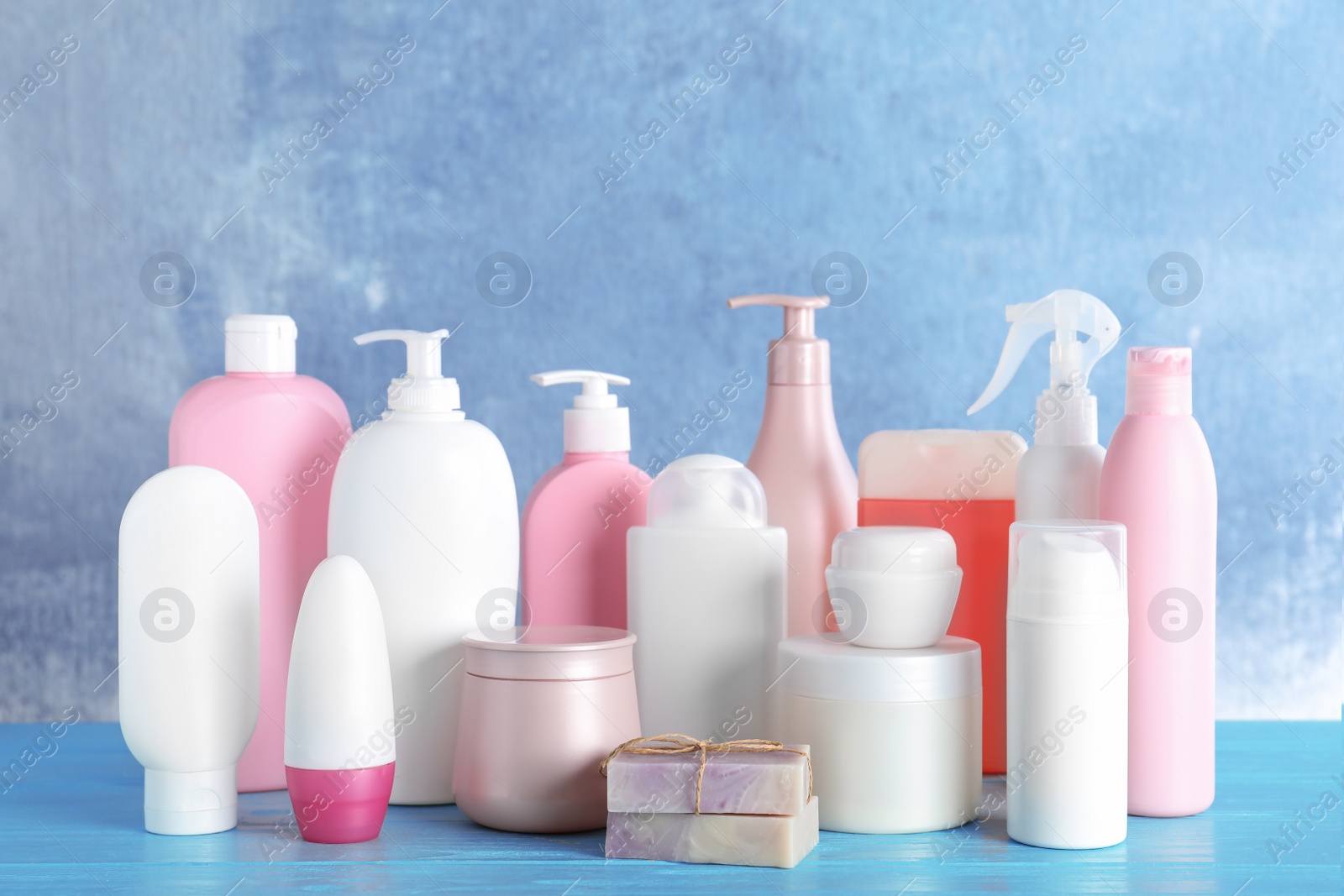 Photo of Different body care products on wooden table against blue background