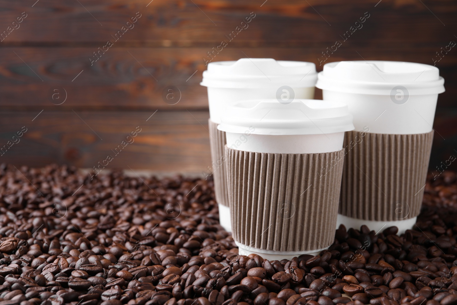 Photo of Coffee to go. Paper cups on roasted beans, space for text