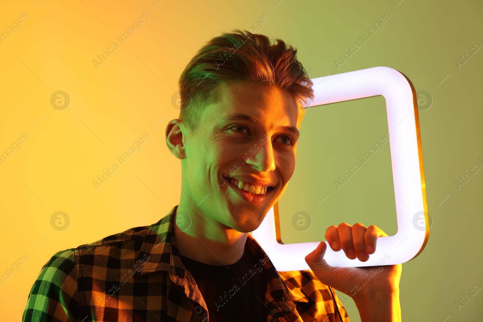 Photo of Young man with square lamp on color background in neon lights