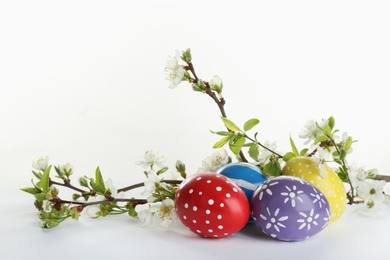 Photo of Painted Easter eggs and blossoming branches on white background