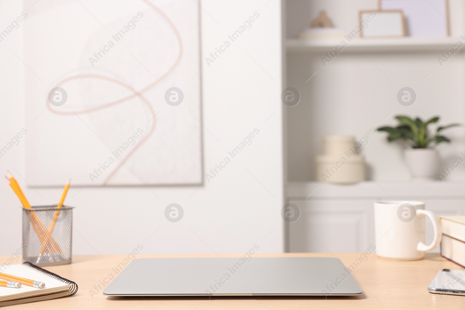 Photo of Home office. Laptop, cup and stationery on wooden desk indoors. Space for text