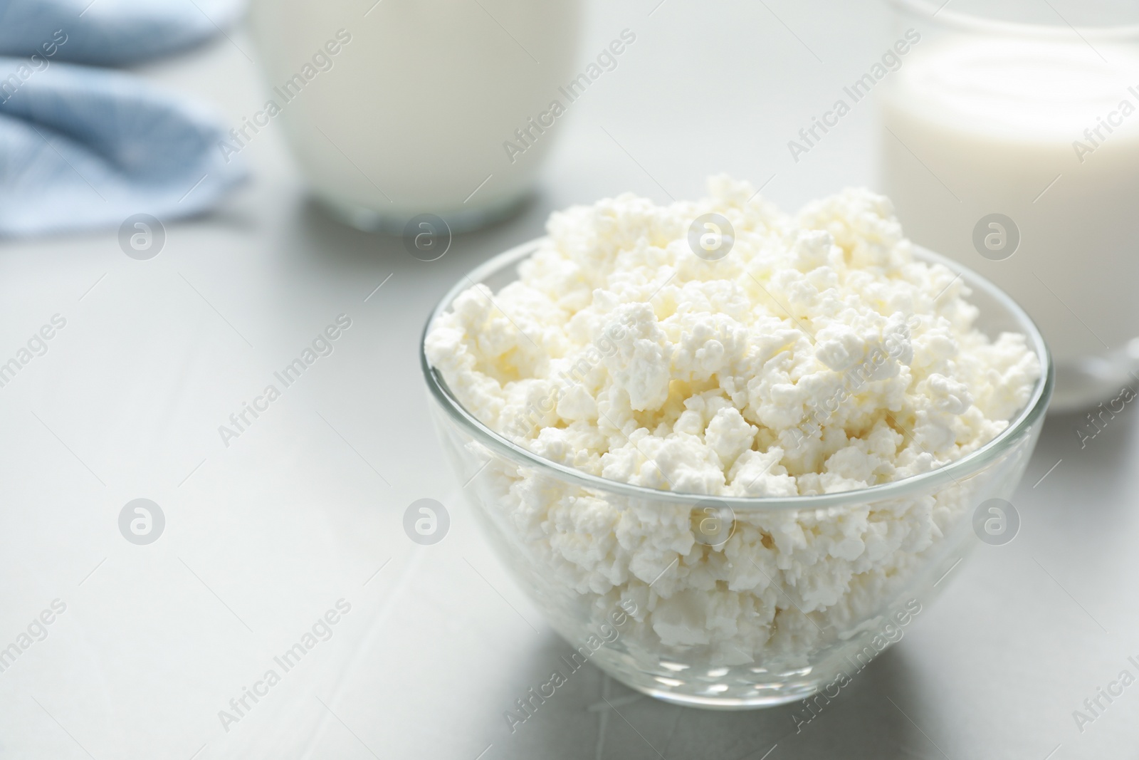 Photo of Delicious fresh cottage cheese in bowl on grey table