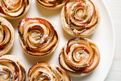 Photo of Freshly baked apple roses on white table, top view. Beautiful dessert