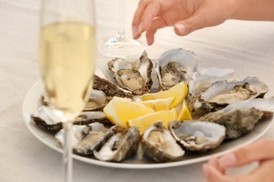 Photo of Woman with fresh oysters at table, focus on hands