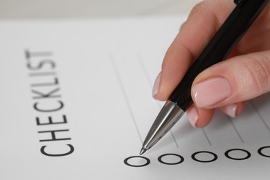 Photo of Woman filling Checklist with pen, closeup view