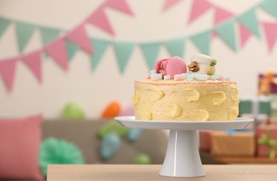 Photo of Delicious cake decorated with macarons and marshmallows on wooden table in festive room, space for text