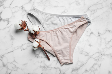 Photo of Women's underwear and cotton flowers on marble background, flat lay