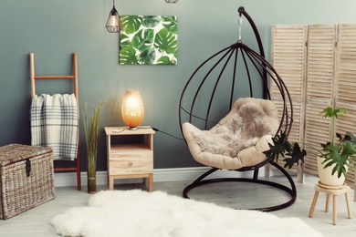 Photo of Elegant living room interior with hanging armchair and fuzzy rug