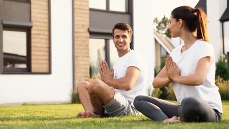 Photo of Sporty couple practicing morning yoga at backyard. Healthy lifestyle