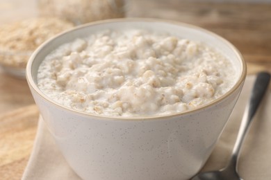 Photo of Tasty boiled oatmeal in bowl on table, closeup