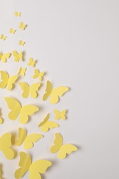 Photo of Yellow paper butterflies on white background, top view. Space for text